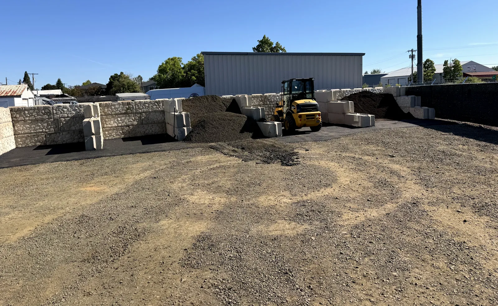 The yard on Queen Ave with its loader and concrete-block bays